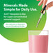 A woman's hand adds liquid from a dropper into a glass of pink beverage containing Liquid Magnesium.