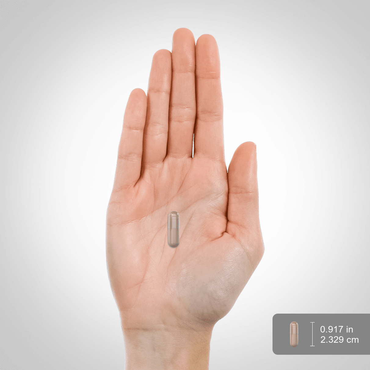 A capsule measuring 0.917 inches (2.329 cm) placed on a hand scale.